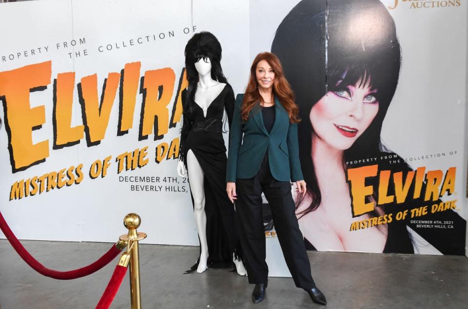 Cassandra Peterson better know as Elvira, Mistress of the Dark, poses next to a mannequin wearing the original dress from “Elvira’s Movie Macabre” during the media preview of Julien’s Auctions year end event “Icons and Idols: Hollywood” in Beverly Hills on November 29, 2021 (AFP via Getty Images)