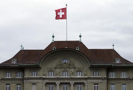 A Swiss national flag flutters in the wind atop the Swiss National Bank SNB headquarters in Bern April 16, 2015. Picture taken April 16. REUTERS/Ruben Sprich