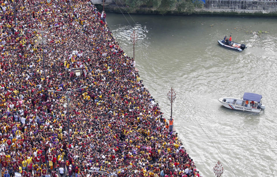 Roman Catholic devotees cross the bridge in a raucous procession