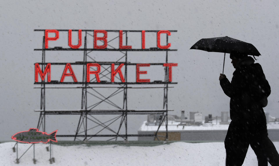 Pedestrians walk near Pike Place Market as snow falls Monday, Feb. 11, 2019, in downtown Seattle. Schools were closed across Washington state as winter snowstorms continued pummeling the Northwest. Seattle's metro area has already been hit by three snowstorms in February, making it the snowiest month in Seattle in more than 30 years. (AP Photo/Ted S. Warren)