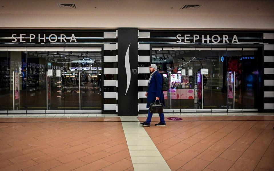 A man walks past the window of the closed Sephora boutique at the Atrium shopping centre in Moscow