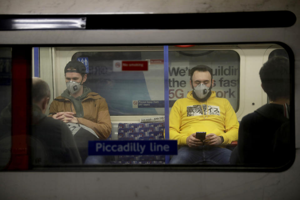 FILE - In this Friday, March 20, 2020 file photo, passengers wearing face masks travel on a Piccadilly Line underground train in London. The World Health Organization on Friday June 5, 2020, broadened its recommendations for the use of masks during the coronavirus pandemic and is now advising that in areas where the virus is spreading, people should wear fabric masks when social distancing is not possible, such as on public transport and in shops. (AP Photo/Matt Dunham, File)