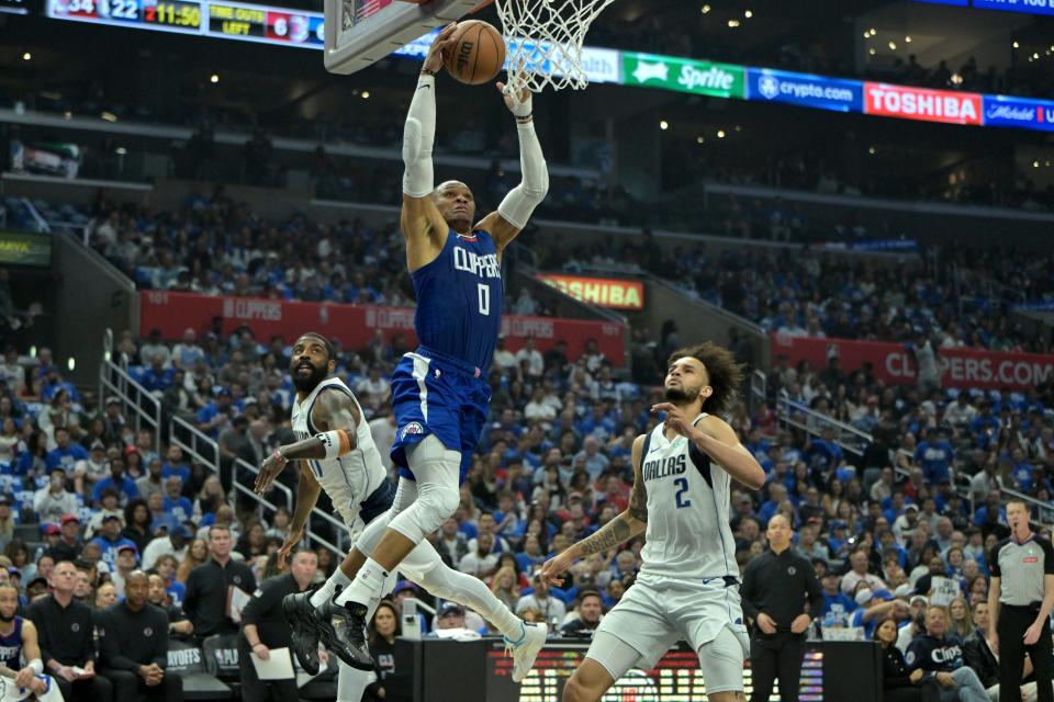 The Los Angeles Clippers' Russell Westbrook drives past the Dallas Mavericks' Kyrie Irving for a dunk.