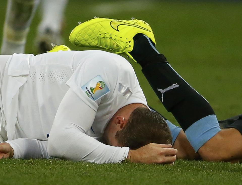 England's Rooney lies on the pitch next to Uruguay's Gimenez during their 2014 World Cup Group D soccer match in Sao Paulo