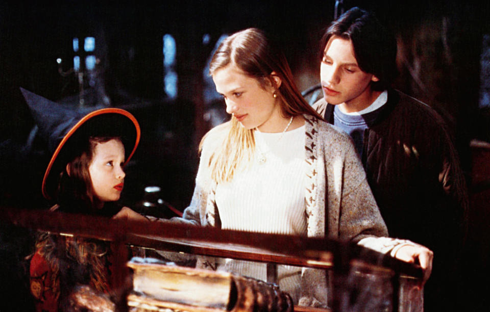 a teen standing with another teen and young child in front of a book