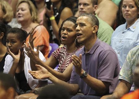 U.S President Barack Obama and first lady Michelle react as they watch the Diamond Head basketball game between Oregon State and Akron during their Christmas vacation in Honolulu, Hawaii, December 22, 2013. REUTERS/Hugh Gentry