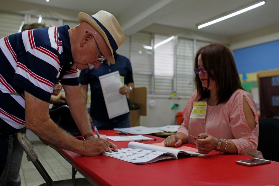 A man signs a voting list before casting his ballot during the referendum for Puerto Rico political status at a polling station in Guaynabo, on June 11, 2017.