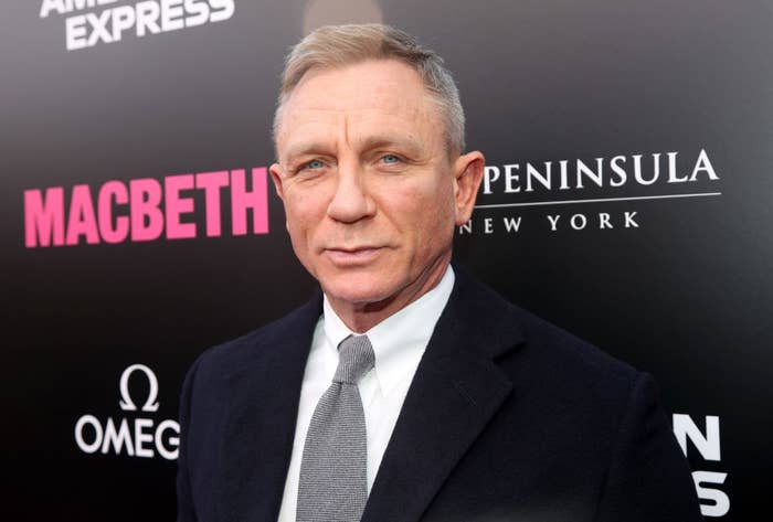 Daniel Craig in a classic suit at the 'Macbeth' premiere, standing before sponsor logos