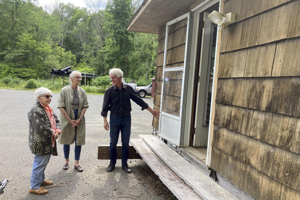 Davyne Verstandig, left, Sarah Griswold, and Marc Olivieri, members of the Arthur Miller Writing Studio board, check on the condition of the former studio of the late American playwright in Roxbury, Conn., Wednesday, June 21, 2023. The studio has been stored for the past five years behind the Roxbury Town Hall, on property used by the town's public works department. The group, along with Miller's daughter Rebecca Miller, hope to raise $1 million to restore the modest structure, relocate it to a nearby local library and create programming that will inspire other writers. (AP Photo/Susan Haigh)
