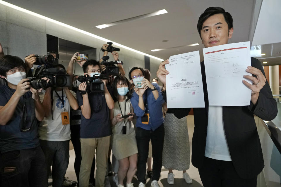 Lawmaker Cheng Chung-Tai displays a document as he is surrounded by reporters after being disqualified from the legislature in Hong Kong, Thursday, Aug. 26, 2021. Hong Kong authorities ousted Cheng from his seat Thursday after finding him to be insufficiently loyal amid Beijing’s tightening grip on the semi-autonomous city. (AP Photo/Vincent Yu)