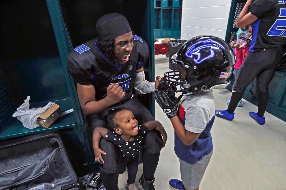 The Detroit Prowl's Tiera Derrick-Jones has fun with her children Ellie, 1, and King Jr., 5, who tries on mom's helmet and gloves in the locker room after their win against the Michigan Queens on Saturday, April 15, 2023, at Allen Park High School.