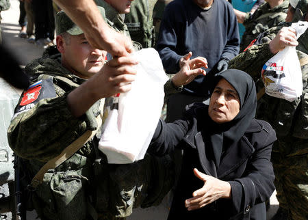 A woman who fled eastern Ghouta receives aid from Russian forces at a shelter in Adra, near Damascus, Syria, March 20, 2018. REUTERS/Omar Sanadiki