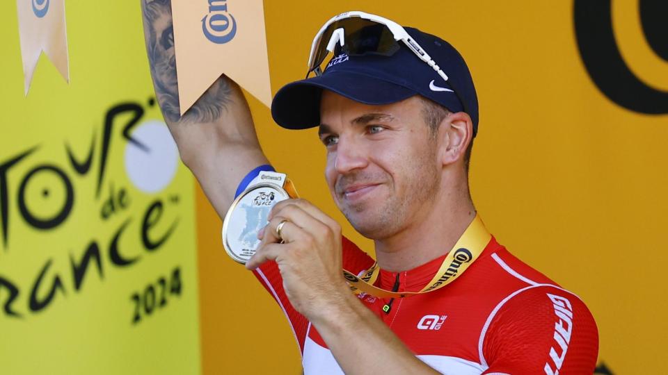 Dylan Groenewegen holds his medal aloft on the podium after winning stage six of the 2024 Tour de France
