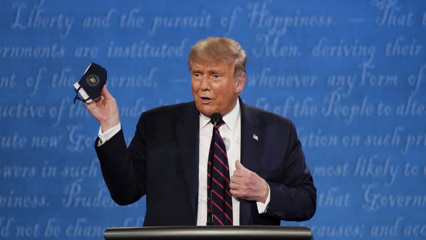 Sept. 29, 2020 photo of President Donald Trump holds up his facemask during the first presidential debate