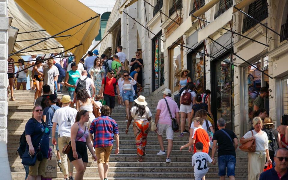 Tourists pass shops lining the Rialto Bridge in Venice - Bloomberg