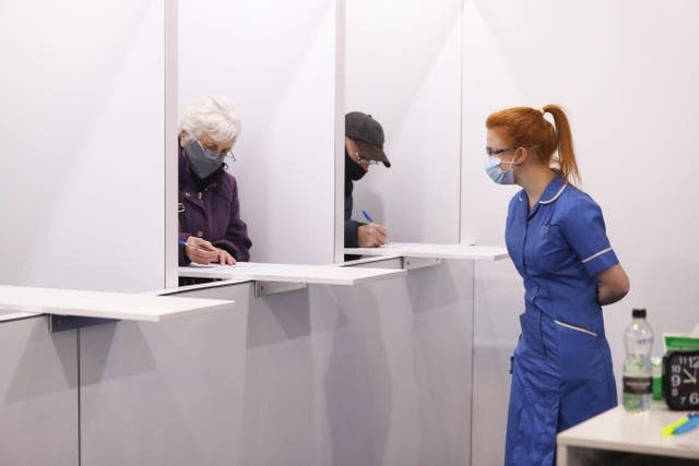 Members of the public fill out paperwork before being given the Oxford/AstraZeneca coronavirus vaccine at the Elland Road vaccination centre in Leeds