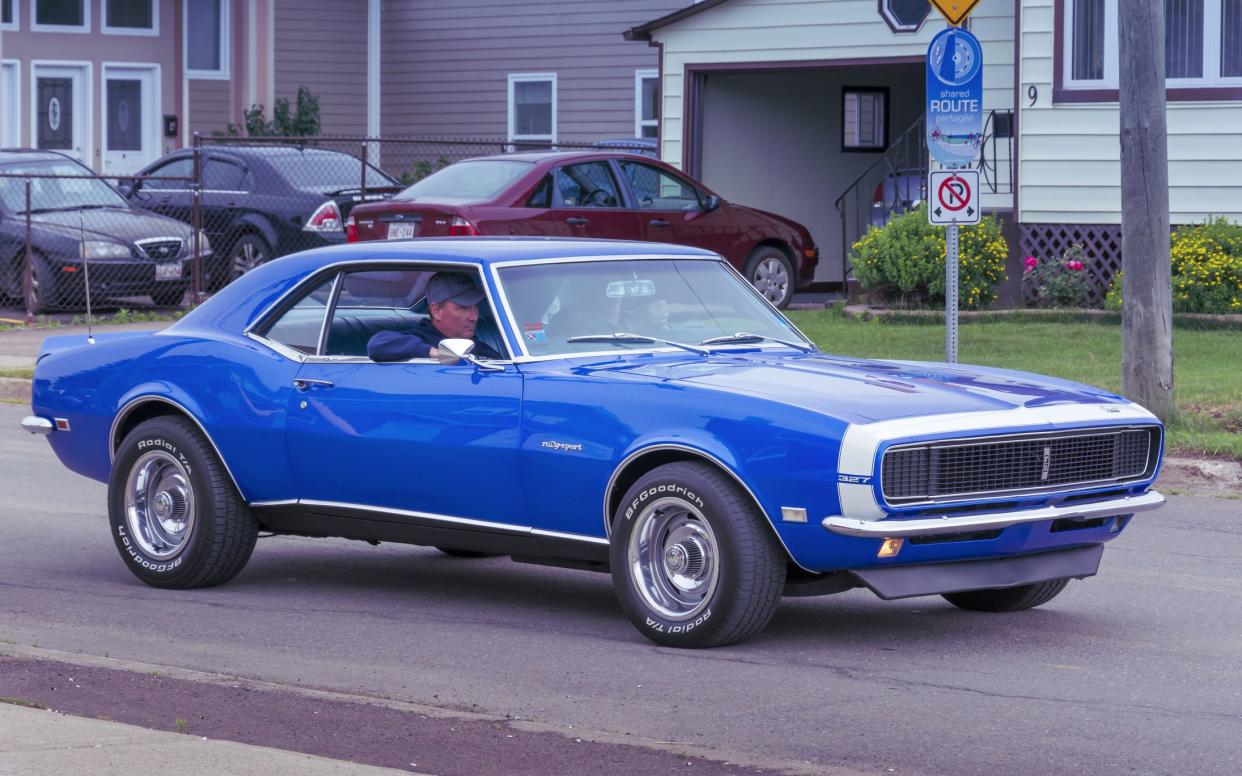 Moncton, New Brunswick, Canada - July 9, 2016 : 1968 Chevrolet Camaro Rally Sport at Mountain Road cruise during 2016 Atlantic Nationals in Moncton, New Brunswick, Canada. Passenger rests his arm on the open window as the classic car drives by.