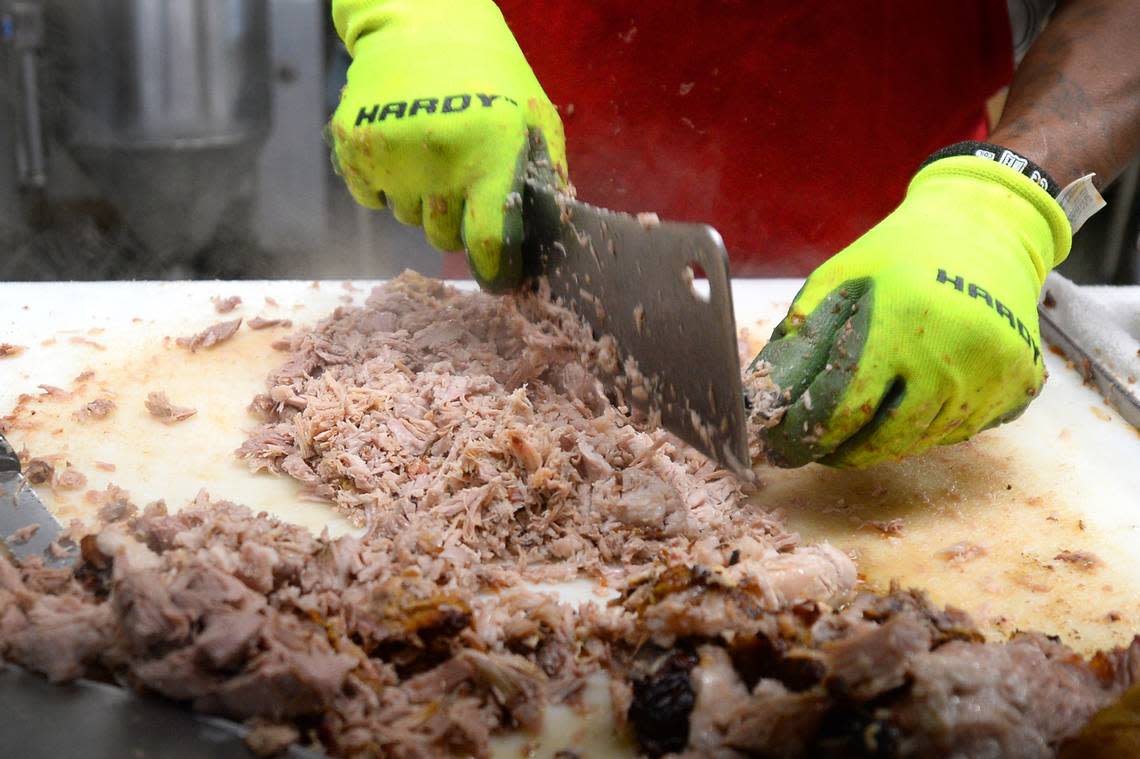 Meat cutter Charles Spikes chops up a pork shoulder at Bridges Barbecue Lodge in Shelby, NC,in time for the lunch crowd on Wednesday, Sept. 1, 2021.