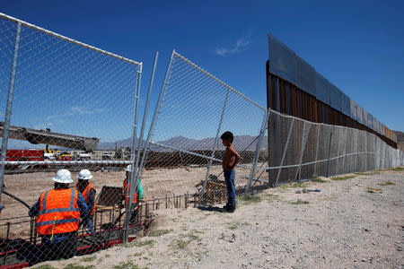 FILE PHOTO: A boy looks at U.S. workers building a section of the U.S.-Mexico border wall at Sunland Park, U.S. opposite the Mexican border city of Ciudad Juarez, Mexico, September 9, 2016. Picture taken from the Mexico side of the U.S.-Mexico border. REUTERS/Jose Luis Gonzalez/File Photo