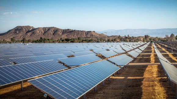 Solar farm in a desert with mountains in the background.