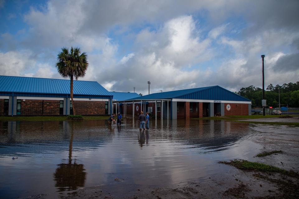 Leon County Schools employees work together to unclog a drain on the campus of Godby High School after Tallahassee experienced torrential rain Thursday, April 11, 2024.