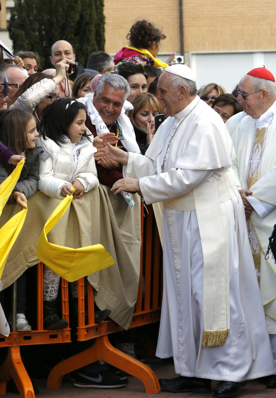 Pope Francis greets faithful as he arrives at the Don Gnocchi Foundation for assistance to disabled and elderly to celebrate the rite of the washing of the feet, in Rome, Thursday, April 17, 2014. Pope Francis has washed the feet of 12 elderly and disabled people — women and non-Catholics among them — in a pre-Easter ritual designed to show his willingness to serve like a "slave." Francis' decision in 2013 to perform the Holy Thursday ritual on women and Muslim inmates at a juvenile detention center just two weeks after his election helped define his rule-breaking papacy. It riled traditionalist Catholics, who pointed to the Vatican's own regulations that the ritual be performed only on men since Jesus' 12 apostles were men. The 2014 edition brought Francis to a center for the elderly and disabled Thursday. Francis kneeled down, washed, dried and kissed the feet of a dozen people, some in wheelchairs. He said the ritual is a gesture of "a slave's service." (AP Photo/Riccardo De Luca)