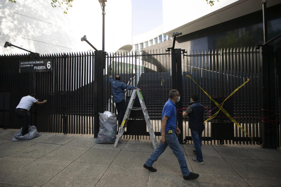 Senate workers remove posters and ribbons placed by demonstrators protesting against Mexican President Andres Manuel Lopez Obrador’s effort to eliminate trust funds which he says are sources of corruption, at an entrance to the Senate in Mexico City, Wednesday, Oct. 21, 2020. The Senate passed various laws on Wednesday eliminating over 100 trusts which finance everything from science to movie productions to disaster relief. (AP Photo/Fernando Llano)