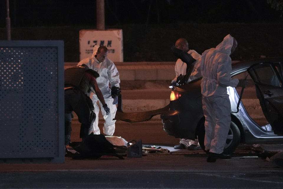 Israeli police inspect the scene of a shooting attack In Hadera, Israel, Sunday, March 27, 2022. A pair of gunmen killed two people and wounded four others in a shooting spree in central Israel before they were killed by police, according to police and medical officials. The identity of the gunmen was not immediately known, but police called them "terrorists," the term usually used for Arab assailants. (AP Photo/Ariel Schalit)