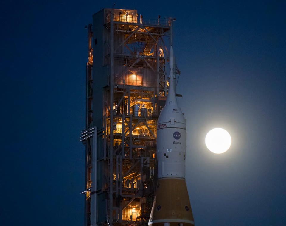 SLS-Orion na plataforma de lançamento com a Lua brilhando no céu e iluminando a área
