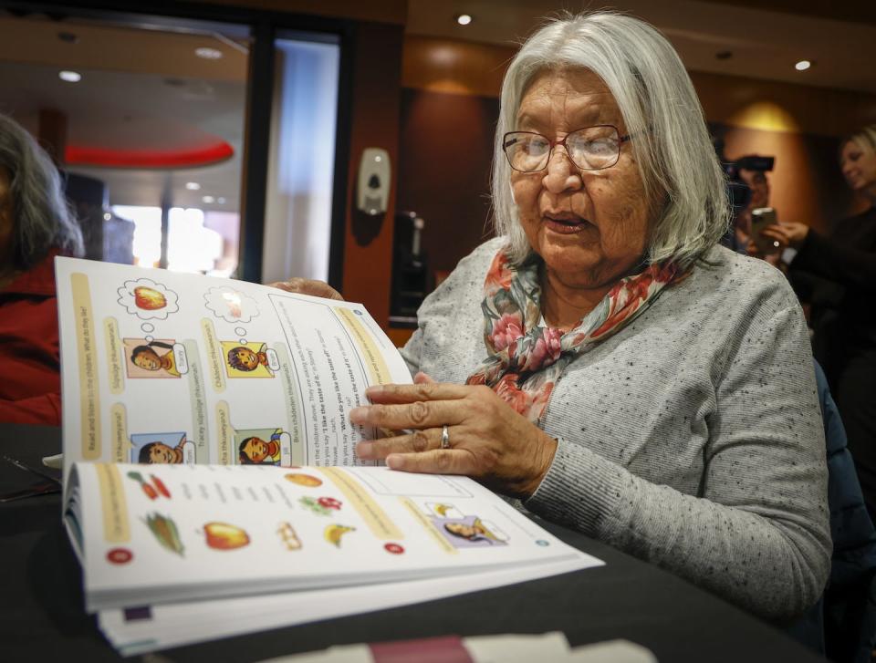 Much of the work to preserve Indigenous languages comes from within communities. Here elder Winnfred Beaver scans through a new textbook of the Stoney language, which is facing extinction, at a ceremony in Kananaskis, Alta. (CP/Jeff McIntosh)