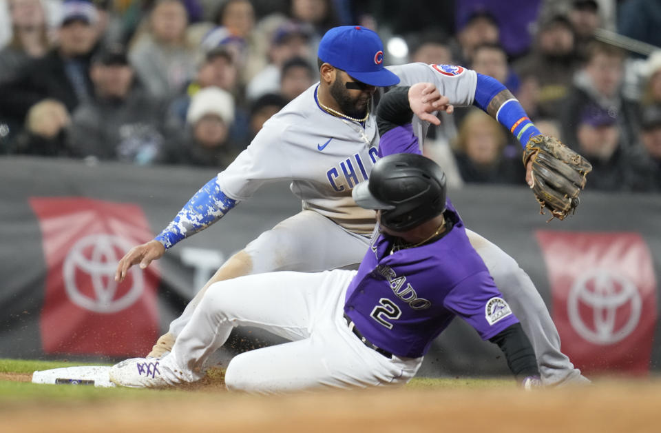 Chicago Cubs shortstop Jonathan Villar, top, fields the throw from the outfield to put out Colorado Rockies' Yonathan Daza, bottom, who was trying to advance from second to third base on a single hit by Kris Bryant in the fifth inning of a baseball game Thursday, April 14, 2022, in Denver. (AP Photo/David Zalubowski)