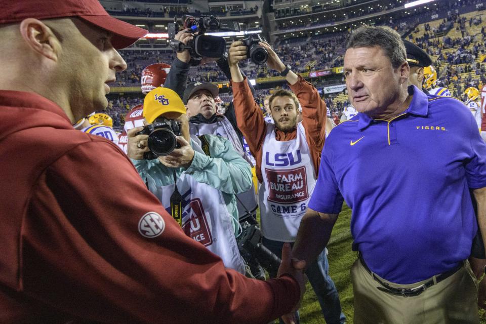 LSU coach Ed Orgeron, right, greets Arkansas coach Barry Lunney Jr. after LSU's 56-20 victory in an NCAA college football game in Baton Rouge, La., Saturday, Nov. 23, 2019. (AP Photo/Matthew Hinton)