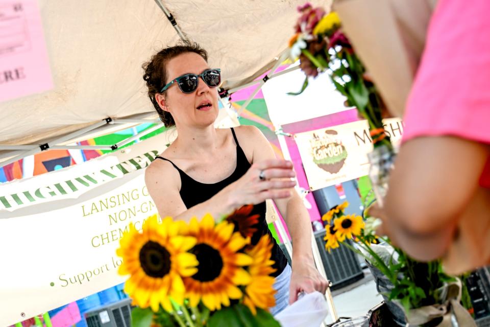 Sarah Browne helps a customer purchase a bouquet at her Highwater Farms booth at the Allen Farmers Market on Wednesday, July 17, 2024, in Lansing.