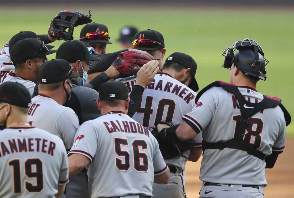 Arizona Diamondbacks starting pitcher Madison Bumgarner is swarmed by teammates as he goes the seven inning distance for a 7-0 shut out over the Atlanta Braves in the second baseball game of a double header Sunday, April 25, 2021, in Atlanta. (Curtis Compton/Atlanta Journal-Constitution via AP)