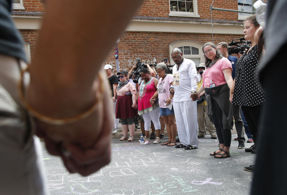 A couple hold hands as the participate in prayers at the intersection where Heather Heyer was killed last year as they mark the anniversary of the Unite the Right rally in Charlottesville, Va., Sunday, Aug. 12, 2018. On that day, white supremacists and counterprotesters clashed in the city streets before a car driven into a crowd struck and killed Heyer. (AP Photo/Steve Helber)