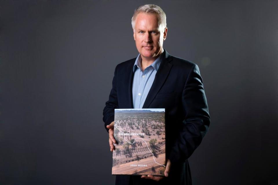 Photographer John Moore poses with his book, Undocumented.