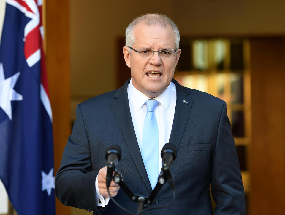 Scott Morrison speaking to the media in front on an Australian flag