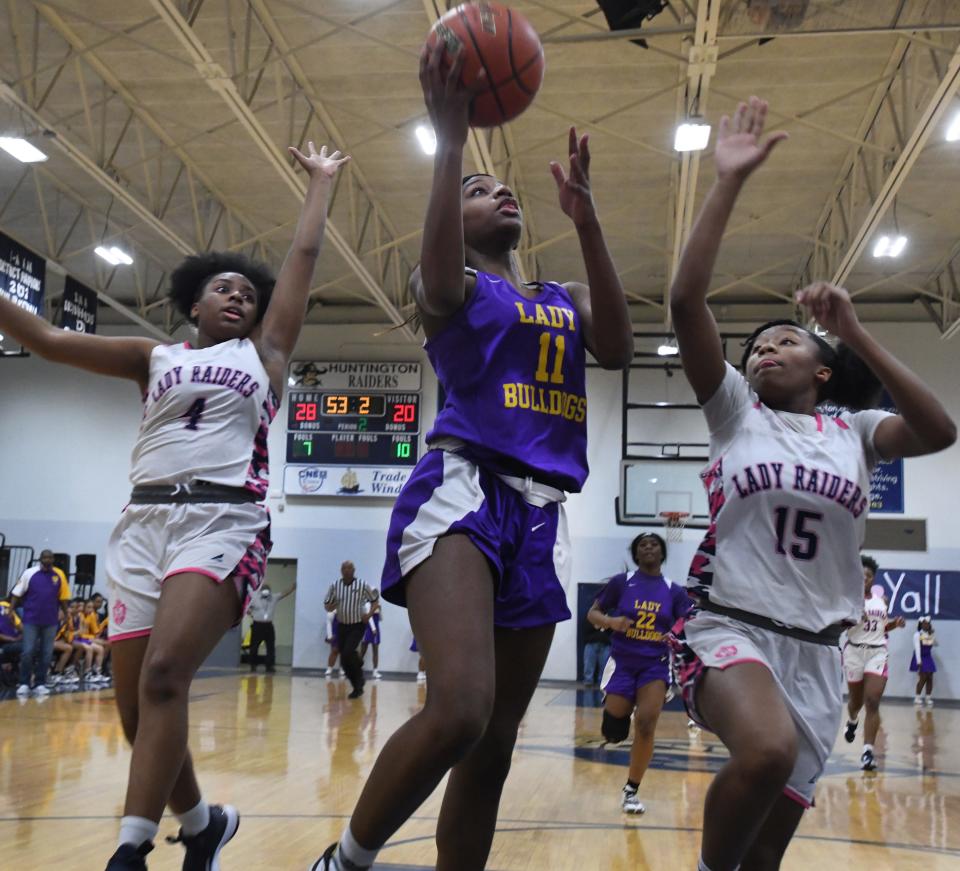 Gibsland-Coleman's Samora Sampson drives to the net against Huntington's Ka'Niya Moore and Jamari Bell.