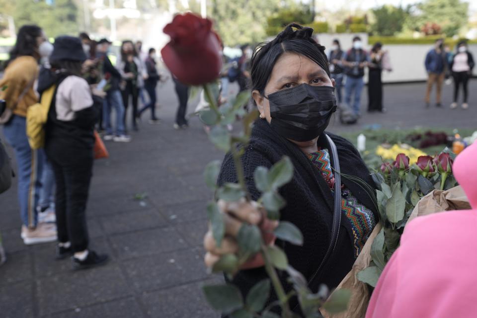 A woman gives roses to the victims of human rights violations during Guatemala's civil war outside the Supreme Court in Guatemala City, Monday, Jan. 24, 2022. A decision at a different court nearby is expected on Monday in the trial of five former civil defense patrolmen, who fought alongside soldiers as civilians, who are accused of sexual assault and human rights violations against dozens of Indigenous women from the Mayan Achi ethnic group. (AP Photo/Moises Castillo)