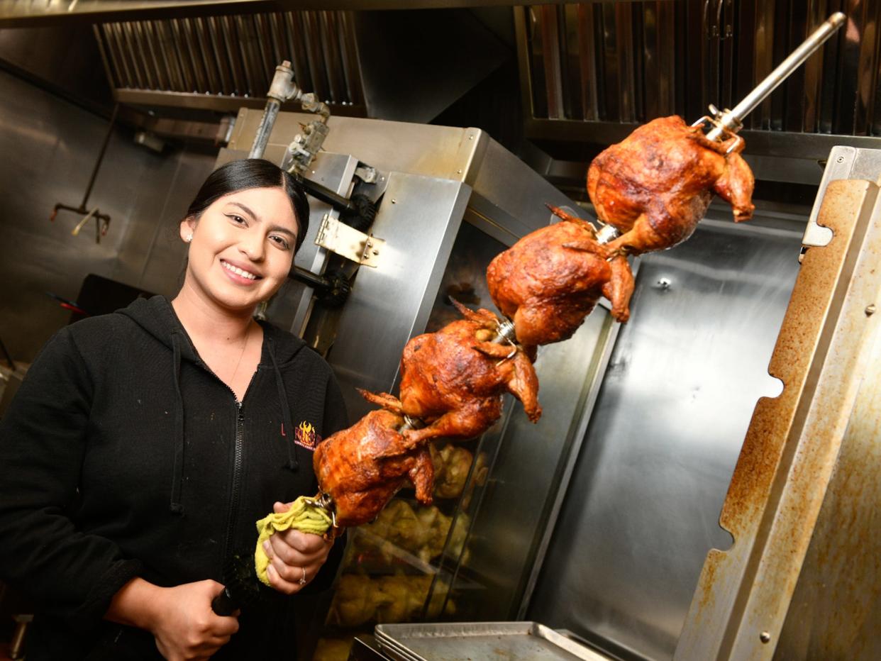 Jennifer, the manager of the Hesperia Pollos Bros restaurant with the restaurant's signature roaster chicken. (James Quigg, for the Daily Press)