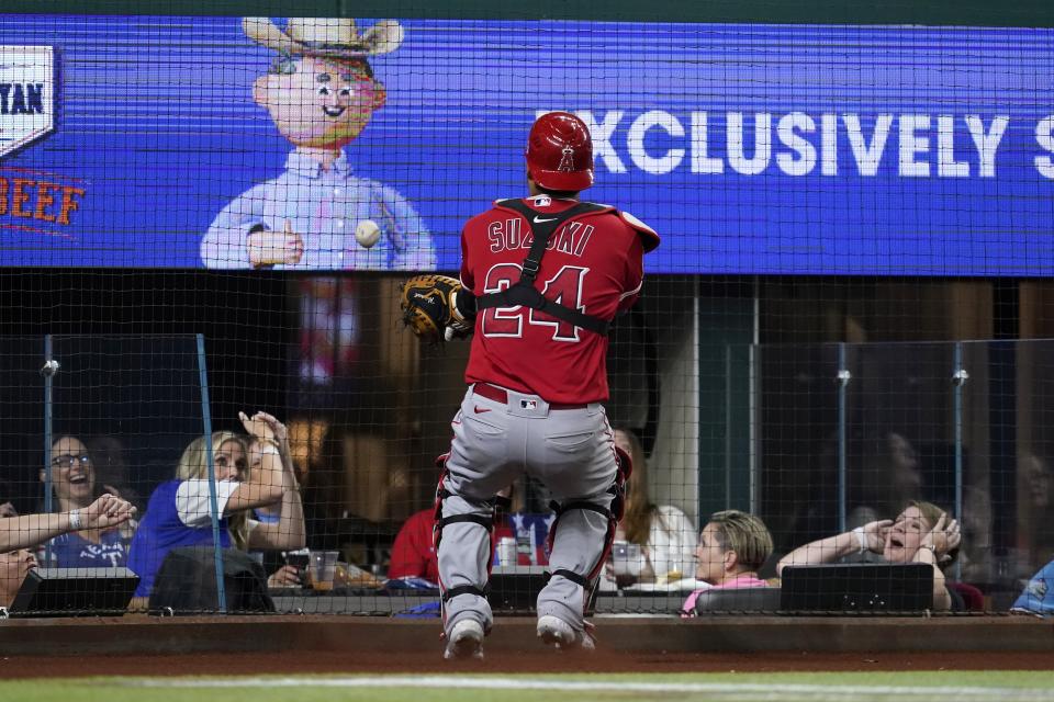 Fans look on as Los Angeles Angels catcher Kurt Suzuki (24) is unable to reach a foul ball hit behind the plate by Texas Rangers' Yonny Hernandez in the sixth inning of a baseball game in Arlington, Texas, Wednesday, Sept. 29, 2021. (AP Photo/Tony Gutierrez)