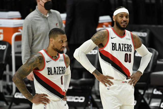Damian Lillard and Carmelo Anthony stand on the court, both with their hands on their hips.