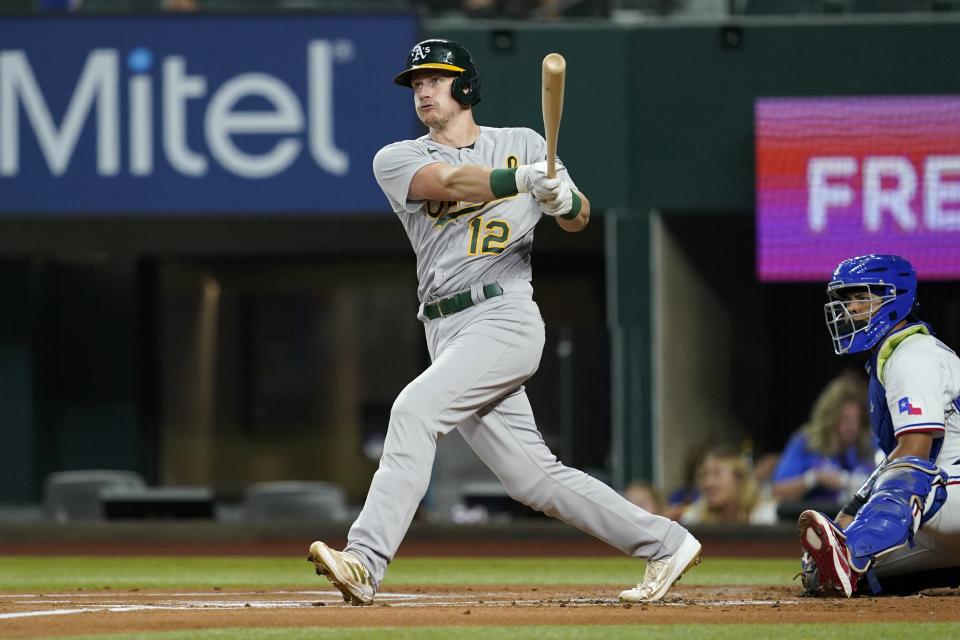 Oakland Athletics' Sean Murphy (12) follows through on a solo home run swing as Texas Rangers catcher Meibrys Viloria looks on in the first inning of a baseball game, Wednesday, Aug. 17, 2022, in Arlington, Texas. (AP Photo/Tony Gutierrez)