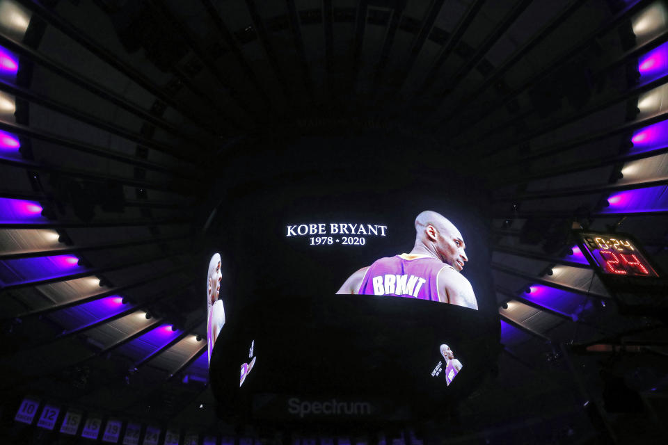 The ceiling of Madison Square Garden is lit in the colors of the Los Angeles Lakers as Kobe Bryant's picture is displayed on a video screen during a moment of silence prior to the start of an NBA basketball game in New York, Sunday, Jan. 26, 2020. Bryant and several others died in a helicopter crash in California Sunday. (AP Photo/Kathy Willens)