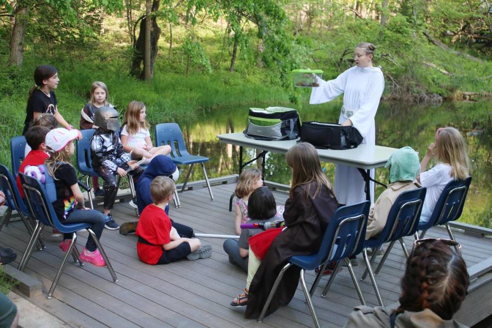 Americorps service member Grace Rockers teaches a group of kids about amphibians in the “Swamps of Dagobah” during Ernie Miller Nature Center’s May the Forest event May 3.