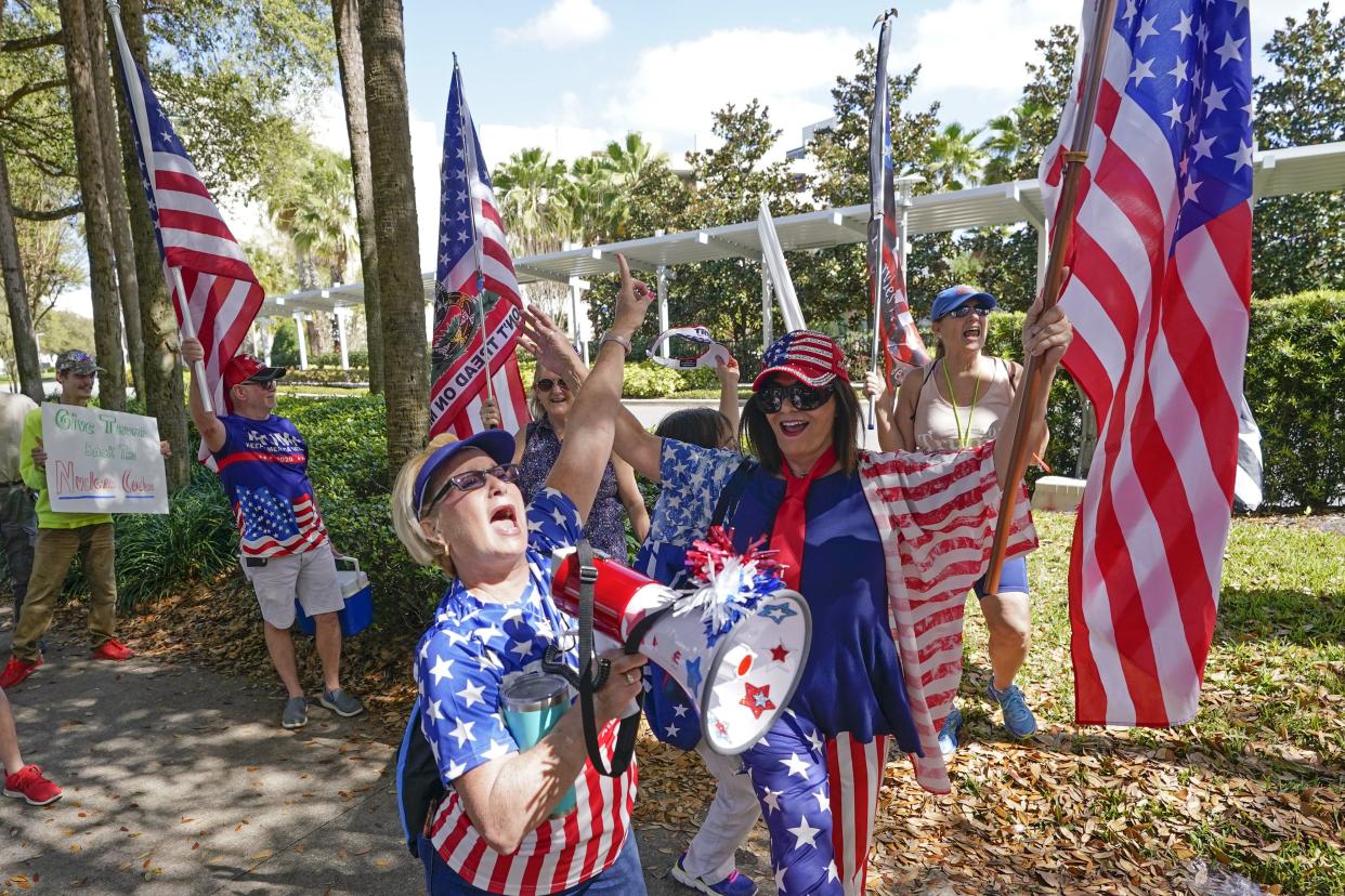 Marcia English, center, leads a group of former President Donald Trump supporters in a song outside the convention center at the Conservative Political Action Conference on Sunday in Orlando, Fla. 