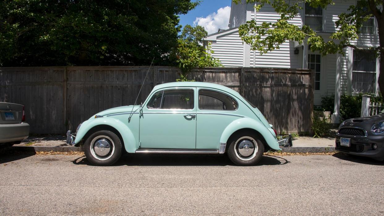 a 1966 vw beetle 1300 parked on the side of the road