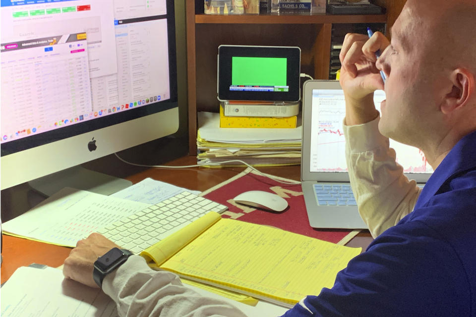 In this image provided by Jay Woods, Woods, a Designated Market Maker with IMC and NYSE Floor Governor, who normally works on the New York Stock Exchange trading floor, works in his home office in Basking Ridge, N.J., Thursday, March 26, 2020. Stocks are opening lower on Wall Street, Friday, March 27, as the market gives back some of the gains it piled up over the past three days. (Shannon Woods/Courtesy Jay Woods via AP)