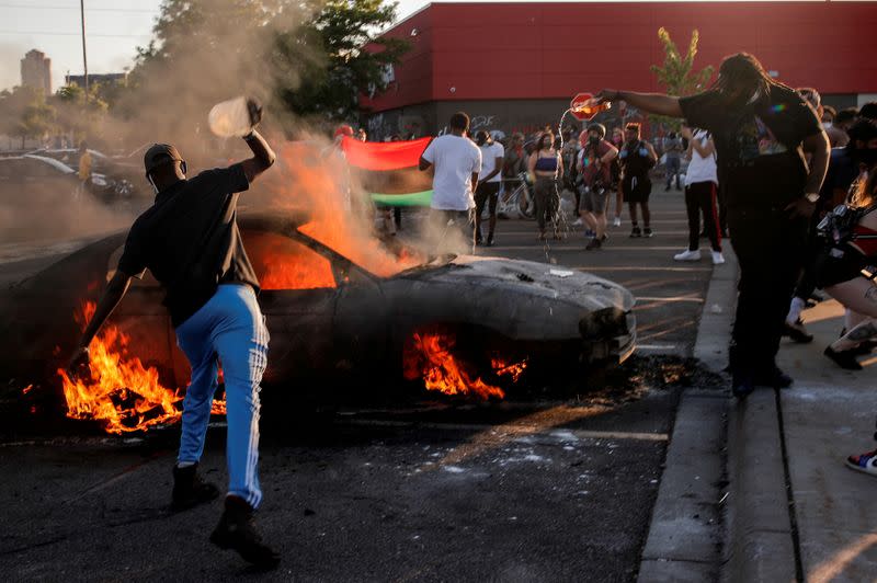 FILE PHOTO: People react as a car burns at the parking lot of a Target store during protests in Minneapolis