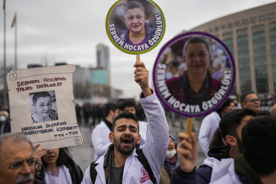 People hold up photographs of Turkish Medical Association President Dr. Sebnem Korur Fincanci, that read in Turkish: "Freedom for Sebnem" and "Sebnem is not alone", during a small rally in her support outside the Justice court in Istanbul, Turkey, Wednesday, Jan. 11, 2023. A court convicted the president of the Turkish Medical Association on Wednesday of disseminating "terror organization propaganda" following a trial that human rights groups had denounced as an attempt to silence government critics. (AP Photo/Francisco Seco)